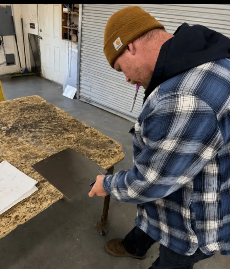 Iron Sight crew member cutting a stainless steel sheet to size in the shop